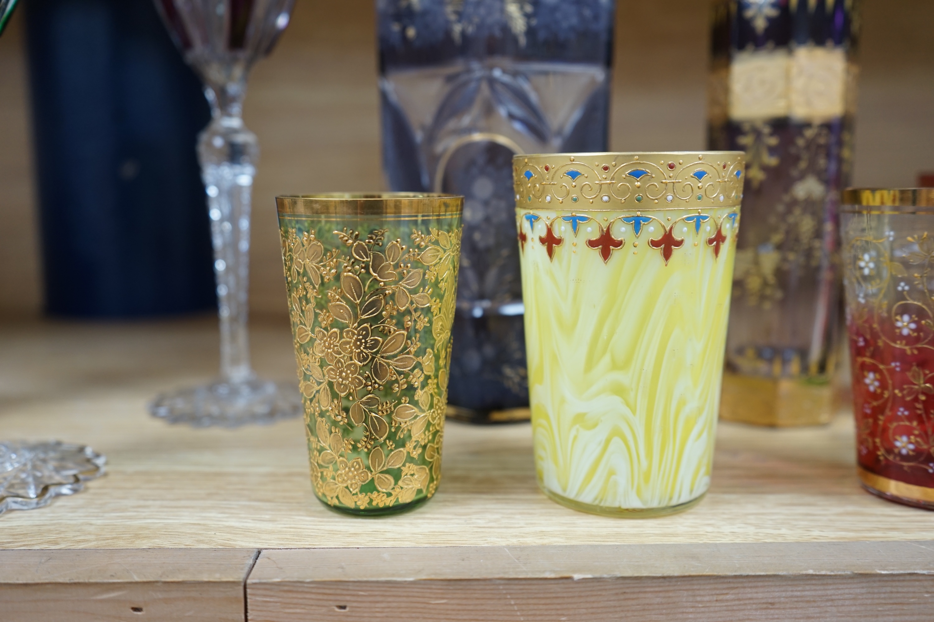 Nine Bohemian decorated glass items including a gilt rimmed and decorated glass inscribed ‘Moser 1503 D553/a’, four smaller glasses, a pair of tall stemmed glasses, 22.5cm, and two vases, tallest 19.5cm. Condition - good